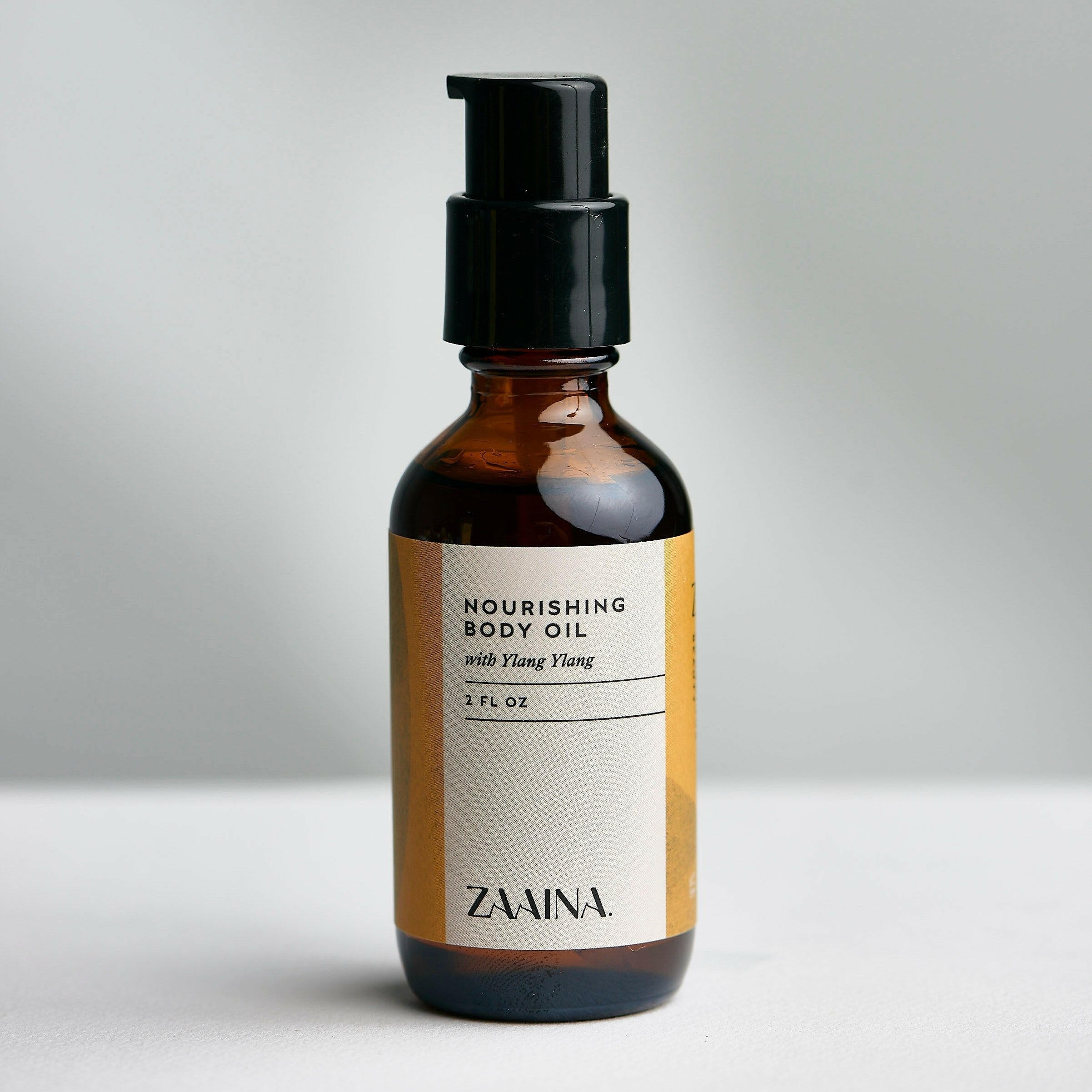 Ylang Ylang body oil bottle displayed with fresh flowers for natural skincare and aromatherapy benefits